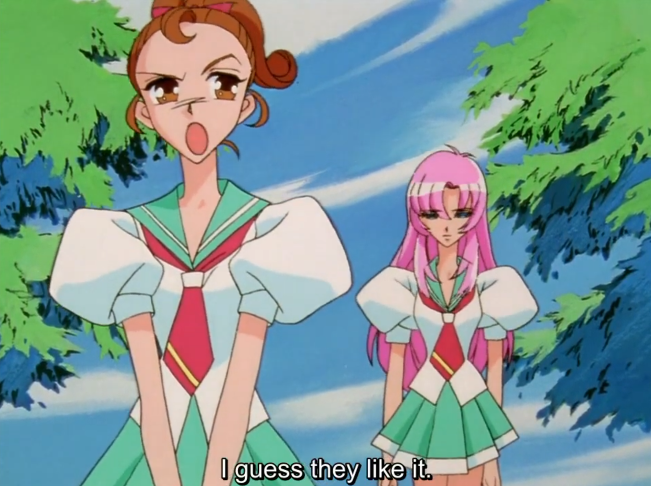 Wakaba, with brown hair in buns, pulls an exasperated face in the foreground while Utena stands behind her looking glum, both in school uniforms under a blue sky and green trees. The subtitle reads "I guess they like it."